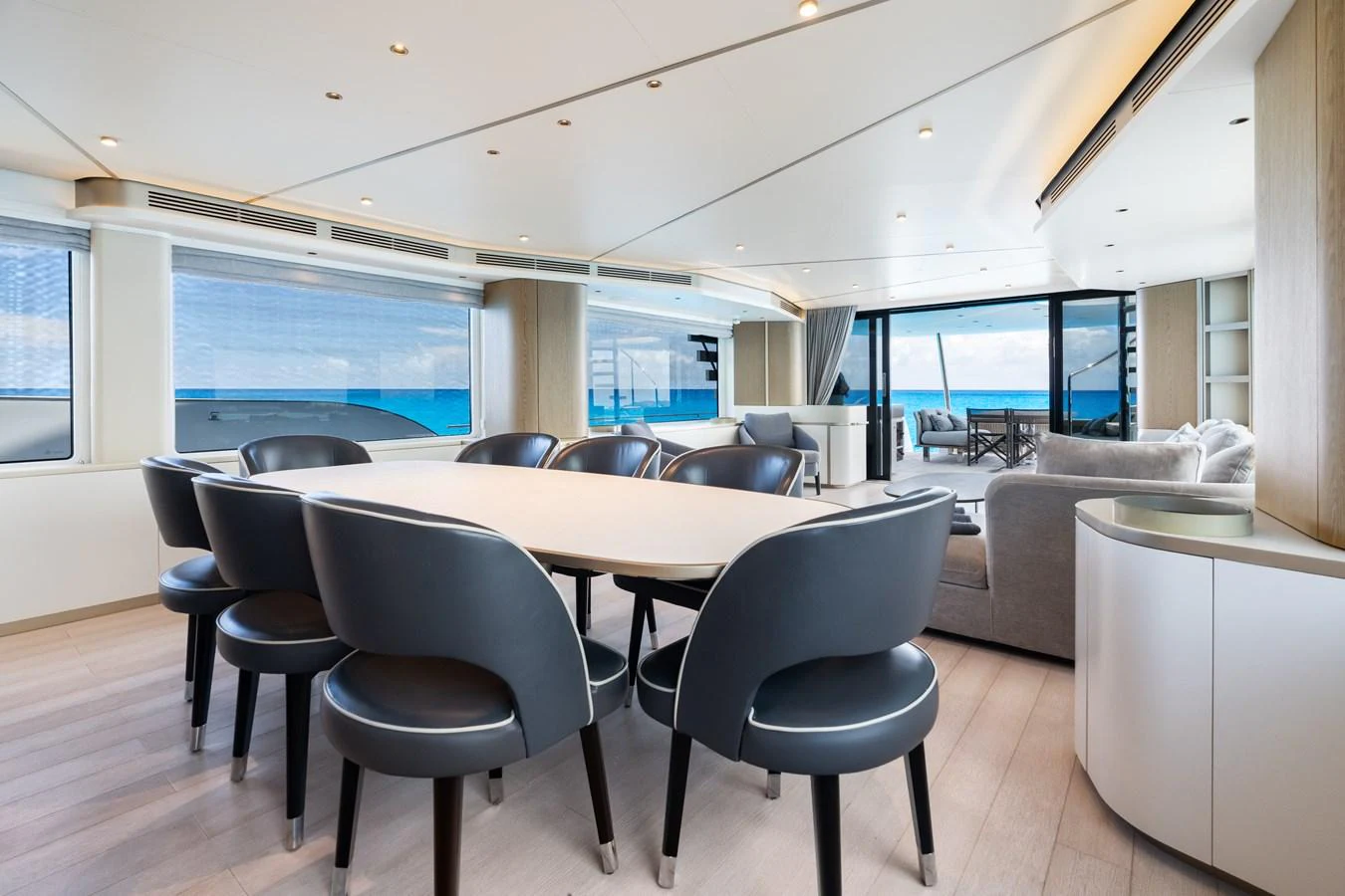 The yacht's dining area features a modern table and stylish chairs with a view of the ocean through large windows. aboard LIFE Yacht for Sale