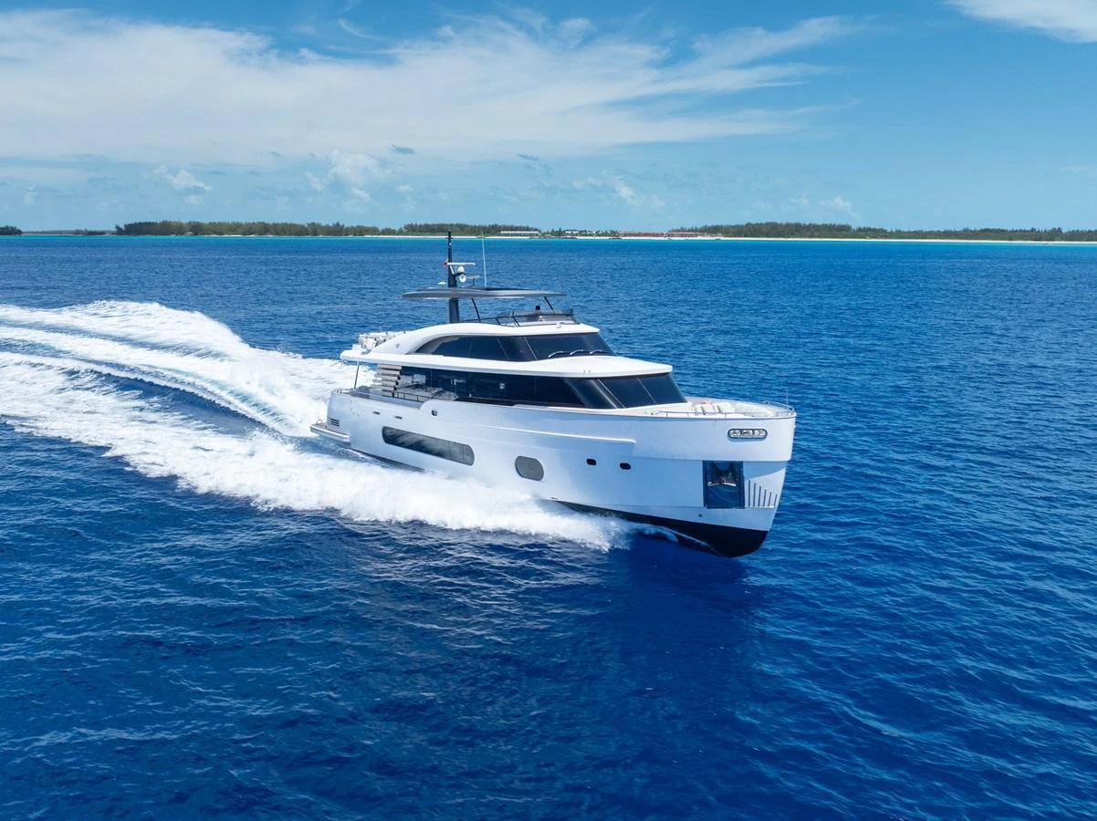 A sleek yacht cruises through the vibrant blue waters under a clear sky. aboard LIFE Yacht for Sale