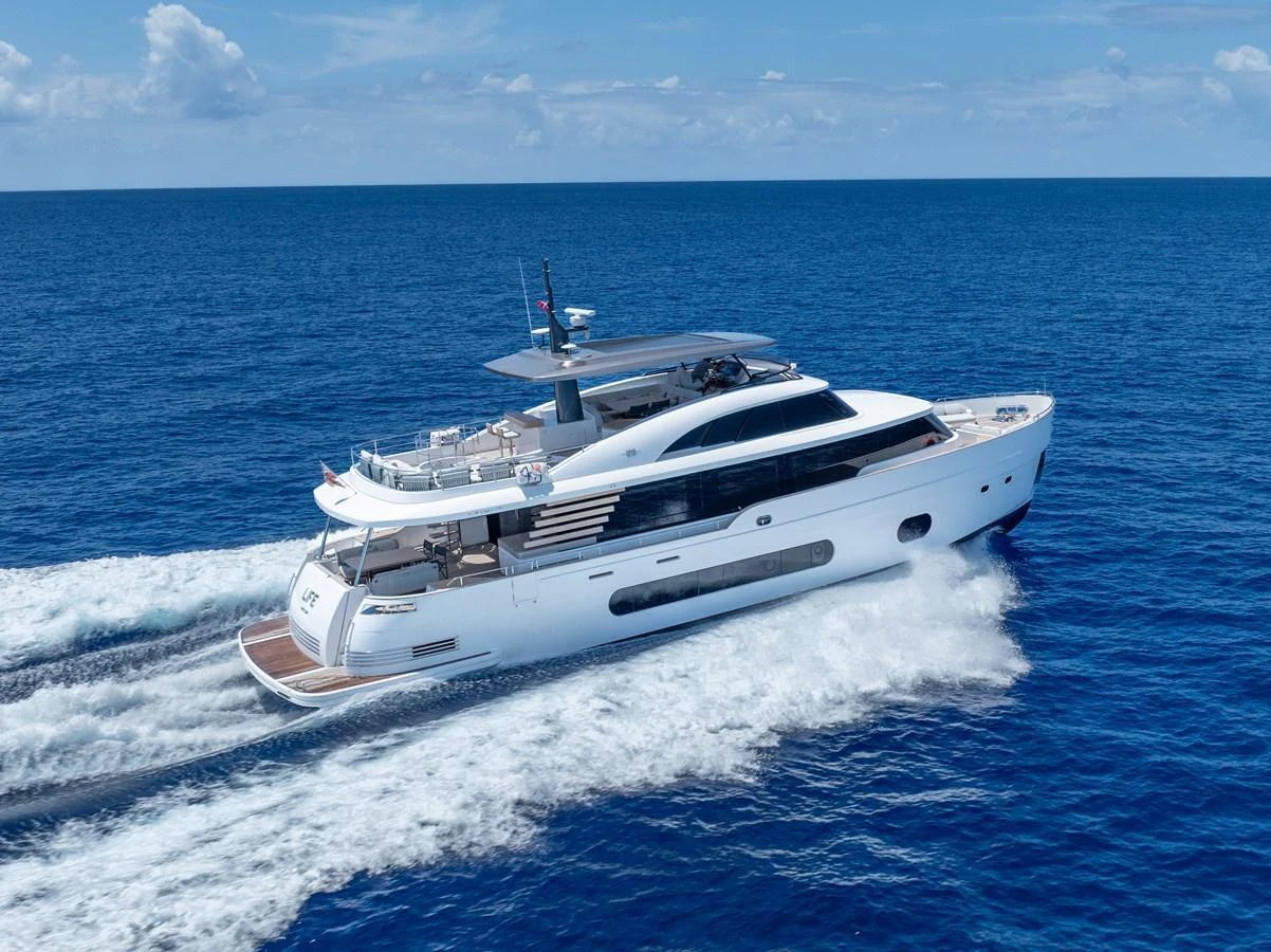 A sleek and modern yacht cruises swiftly through the open sea under a clear blue sky. aboard LIFE Yacht for Sale