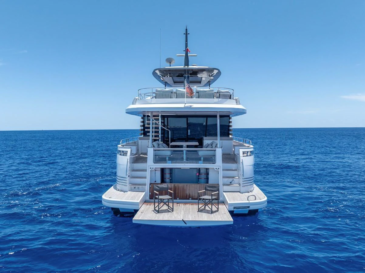 A luxurious yacht is anchored in the serene blue waters, showcasing its spacious aft deck with elegant seating. aboard LIFE Yacht for Sale