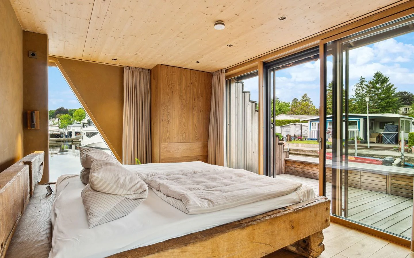 A cozy stateroom with a large bed and sliding glass doors offering a view of the marina. aboard OHANA Yacht for Sale