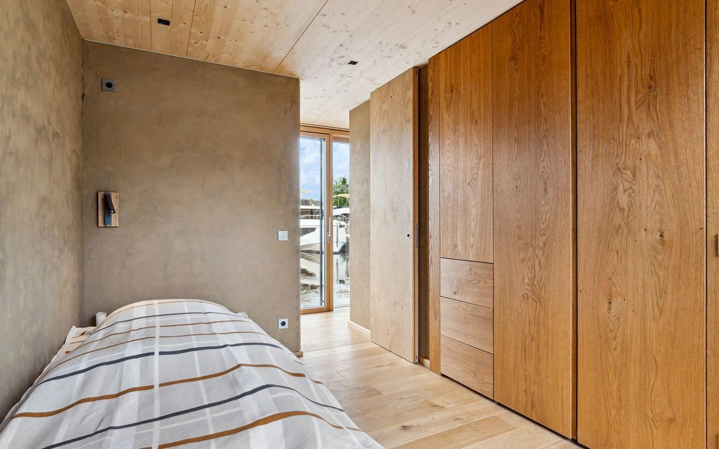 A cozy stateroom with wooden finishes and a large window offering natural light. aboard OHANA Yacht for Sale