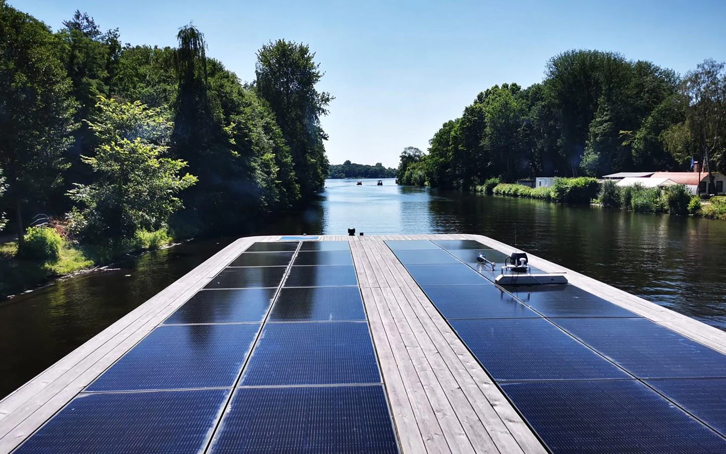 The image showcases the yacht's expansive solar panel array on a serene waterway. aboard OHANA Yacht for Sale