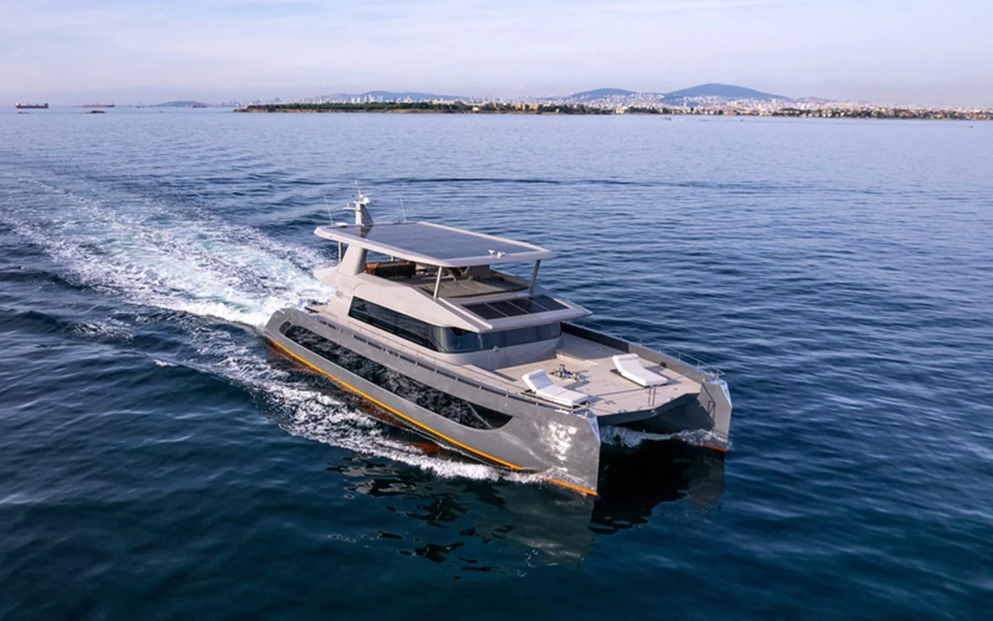 A sleek, modern yacht cruises through calm waters with a scenic coastline in the background. aboard SITARA Yacht for Sale