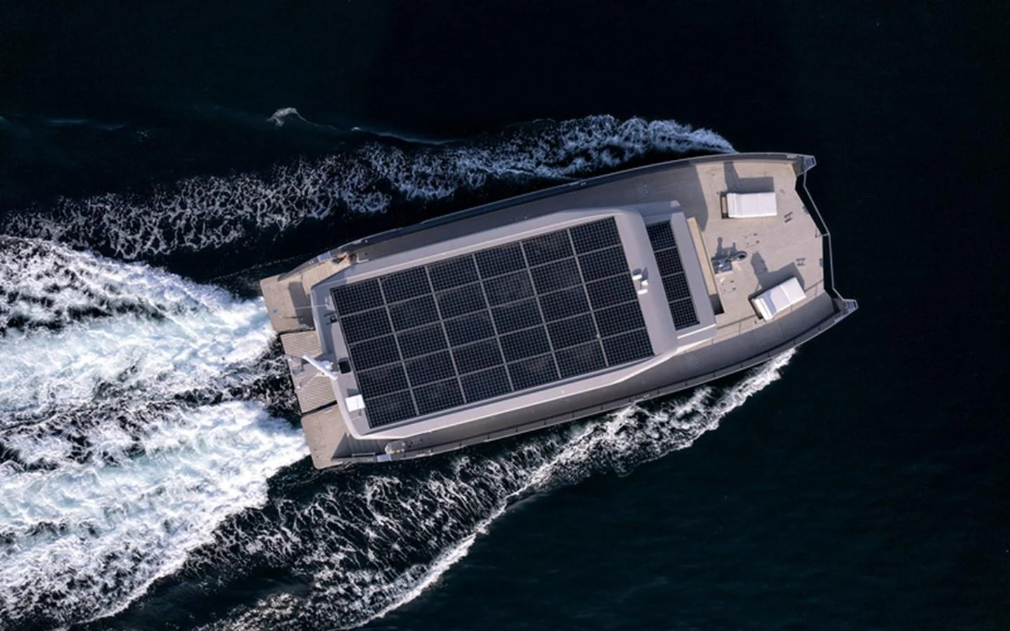 An aerial view of a sleek yacht cruising through the water, showcasing its solar panel-covered deck. aboard SITARA Yacht for Sale