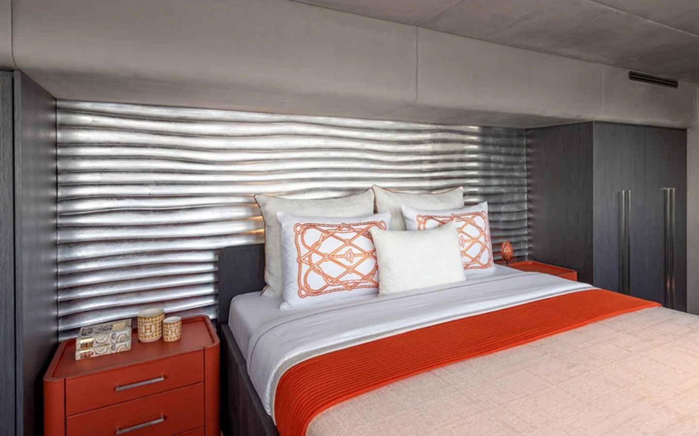 A modern stateroom featuring a stylish bed with orange accents and a textured headboard. aboard SITARA Yacht for Sale