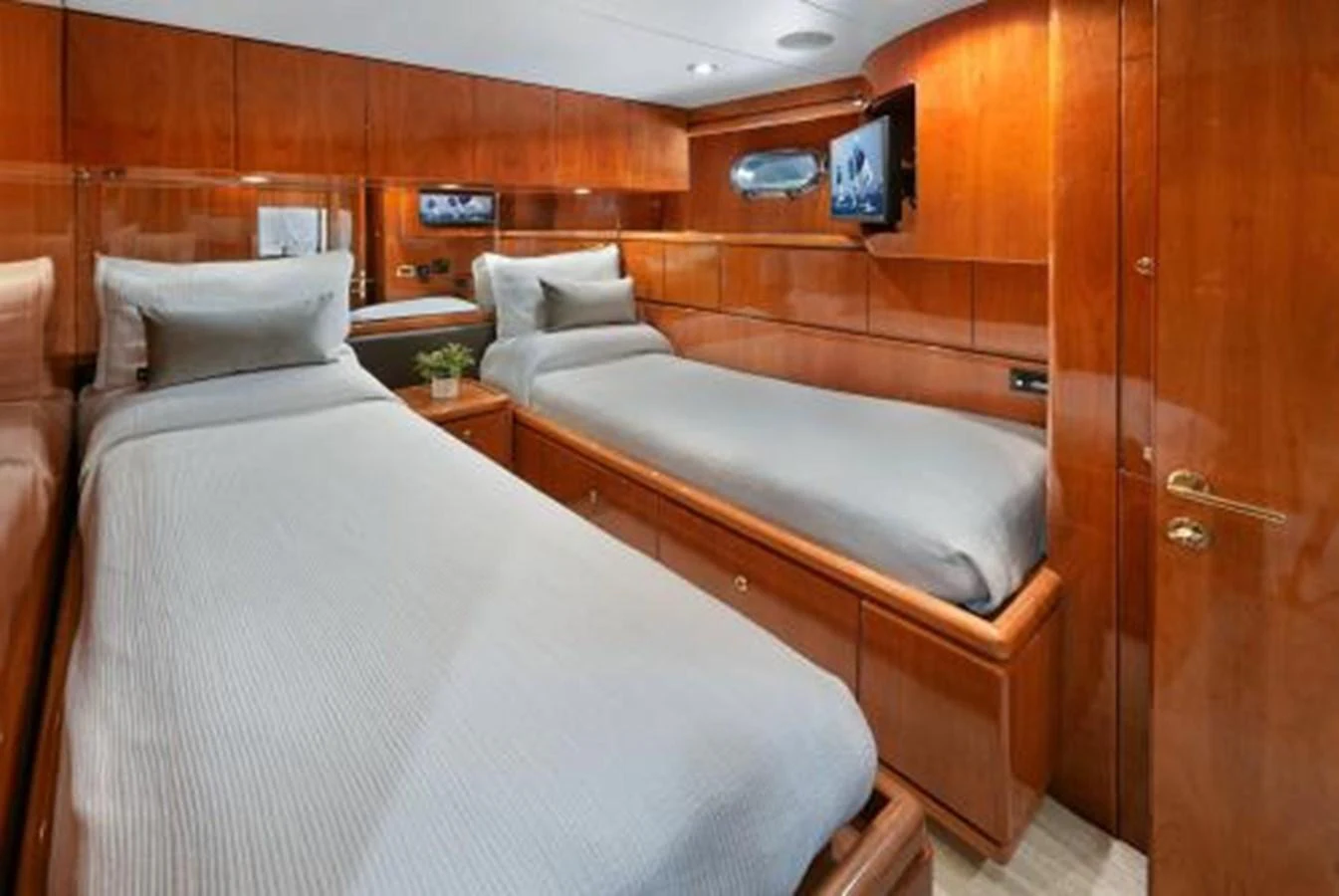 The twin stateroom features two comfortable single beds with elegant wooden cabinetry and a mounted TV for entertainment. aboard SUE CAROLYN Yacht for Sale