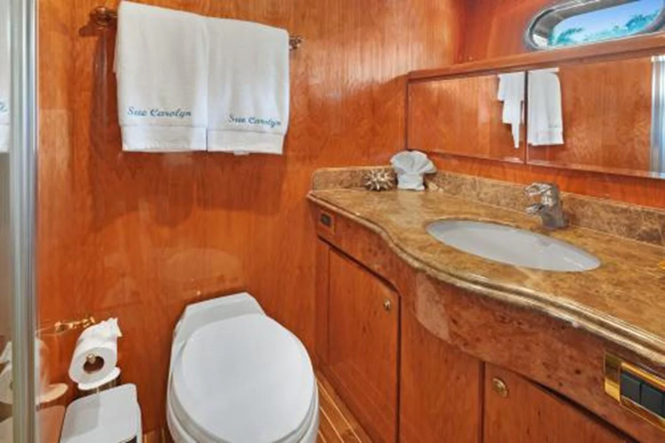 A well-appointed yacht bathroom with wooden cabinetry and a marble countertop. aboard SUE CAROLYN Yacht for Sale