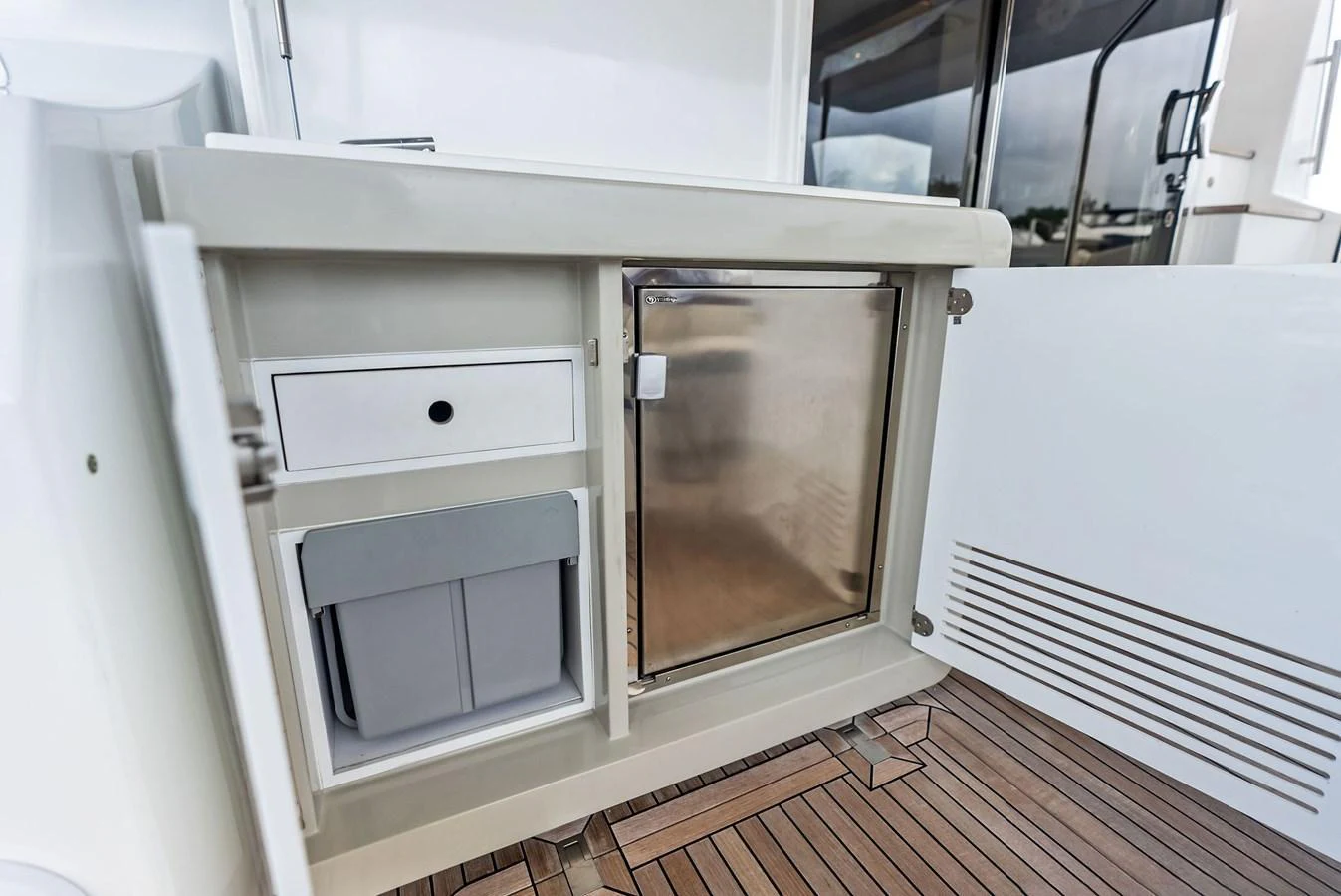 A close-up view of a yacht's built-in storage and refrigeration unit on a teak deck. aboard CLASS DISMISSED Yacht for Sale