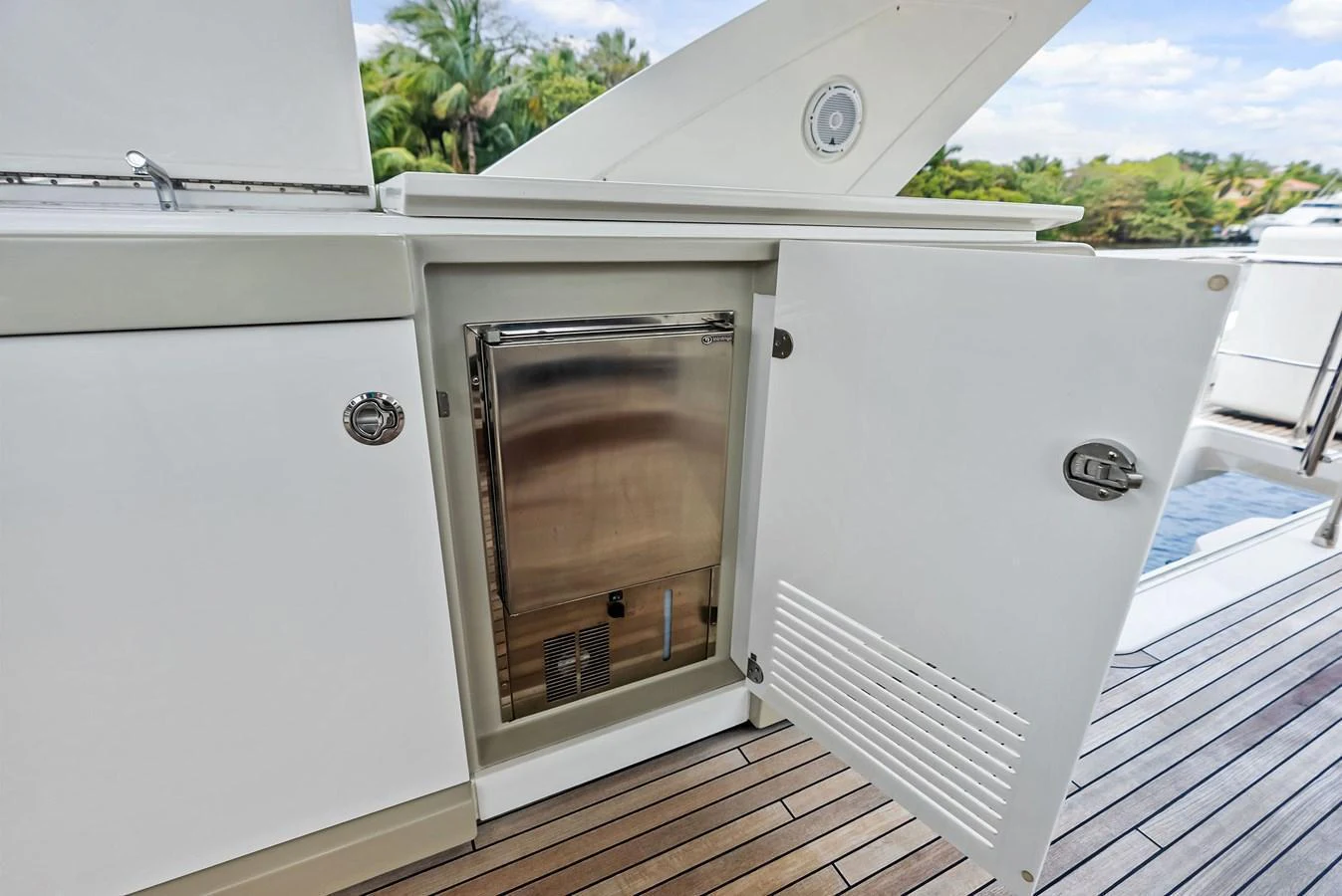 A close-up view of an open cabinet on the yacht's deck, revealing a stainless steel appliance inside. aboard CLASS DISMISSED Yacht for Sale