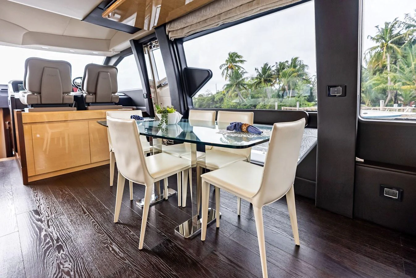 The yacht's dining area features a sleek glass table with modern white chairs, set against large windows offering scenic views. aboard CLASS DISMISSED Yacht for Sale