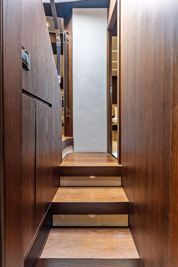 A narrow wooden staircase leads to the upper level of the yacht's interior. aboard CLASS DISMISSED Yacht for Sale