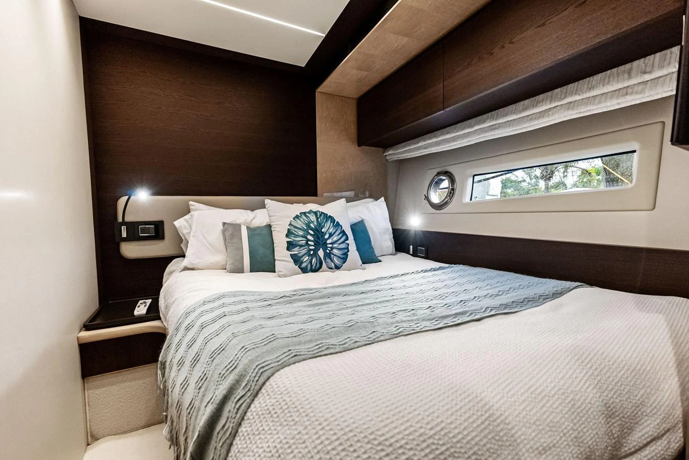 A cozy stateroom featuring a comfortable bed with decorative pillows and a window providing natural light. aboard CLASS DISMISSED Yacht for Sale