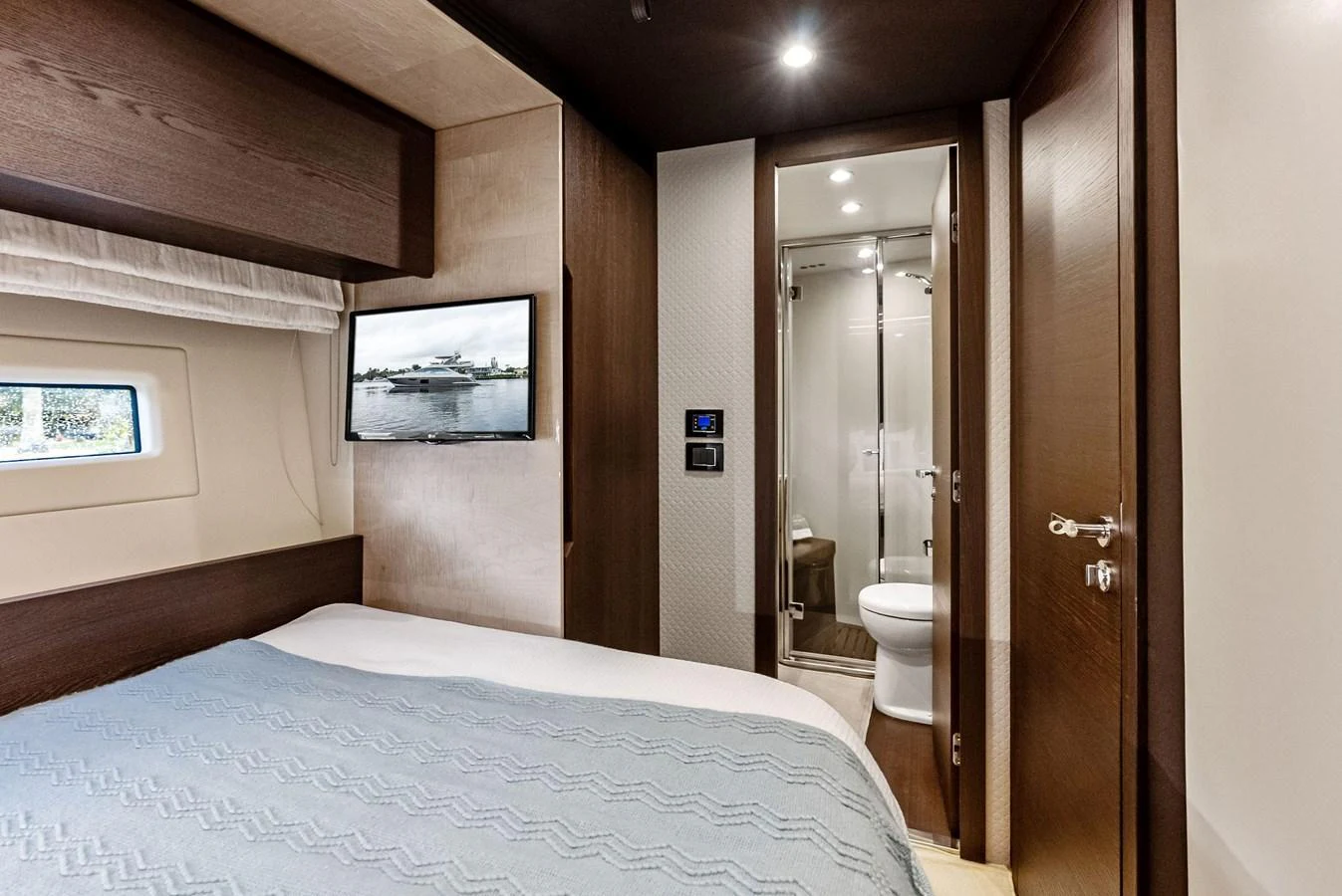 The guest stateroom features a cozy bed, a wall-mounted TV, and an en-suite bathroom. aboard CLASS DISMISSED Yacht for Sale