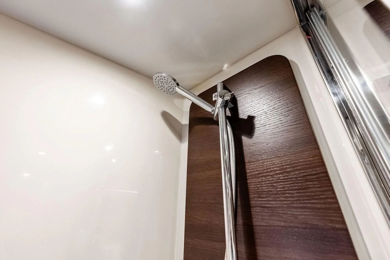 A sleek and modern shower area with a chrome showerhead and wood paneling. aboard CLASS DISMISSED Yacht for Sale