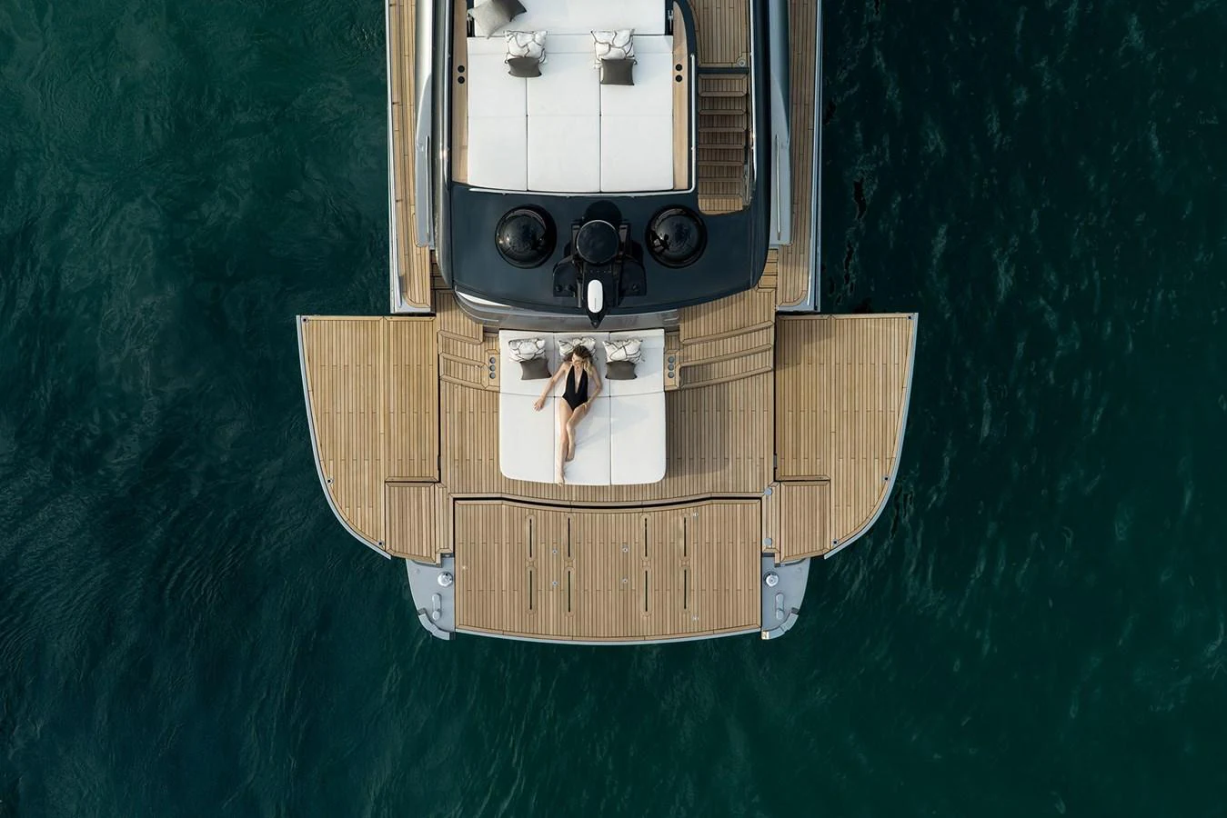 A luxurious aft deck with a sunbathing area and elegant wooden flooring, set against the backdrop of the sea. aboard GTX70 Yacht for Sale