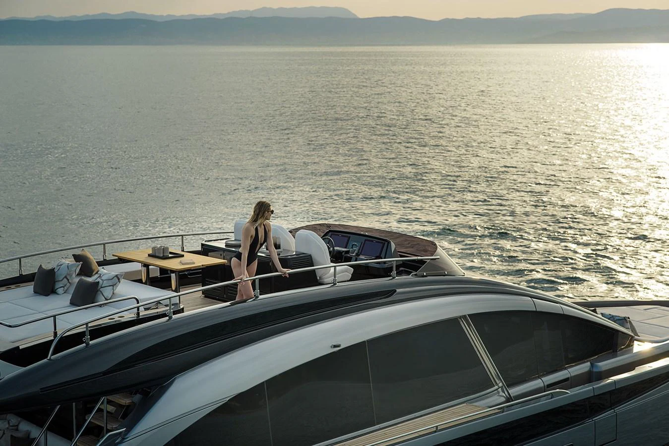 A serene view of the yacht's flybridge with a person enjoying the sunset over the water. aboard GTX70 Yacht for Sale