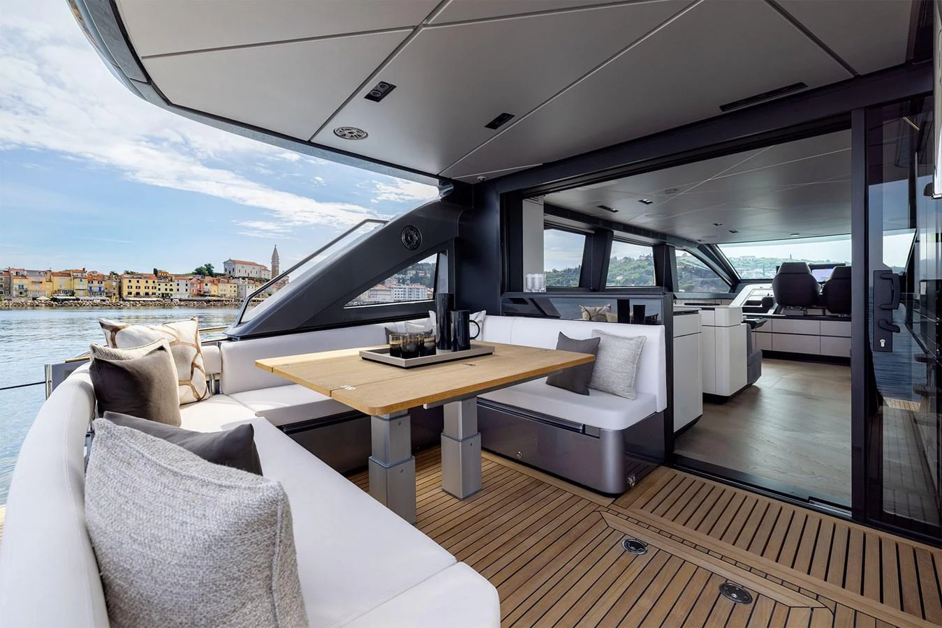 The aft deck features a stylish dining area with a wooden table and plush seating, seamlessly blending indoor and outdoor spaces. aboard GTX70 Yacht for Sale