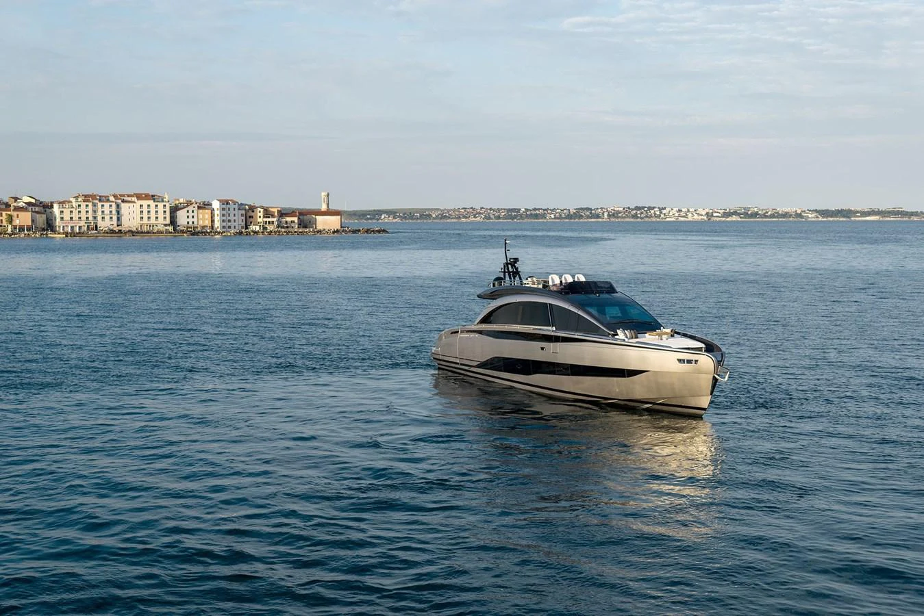 A sleek, modern yacht cruises on calm waters with a scenic coastal backdrop. aboard GTX70 Yacht for Sale