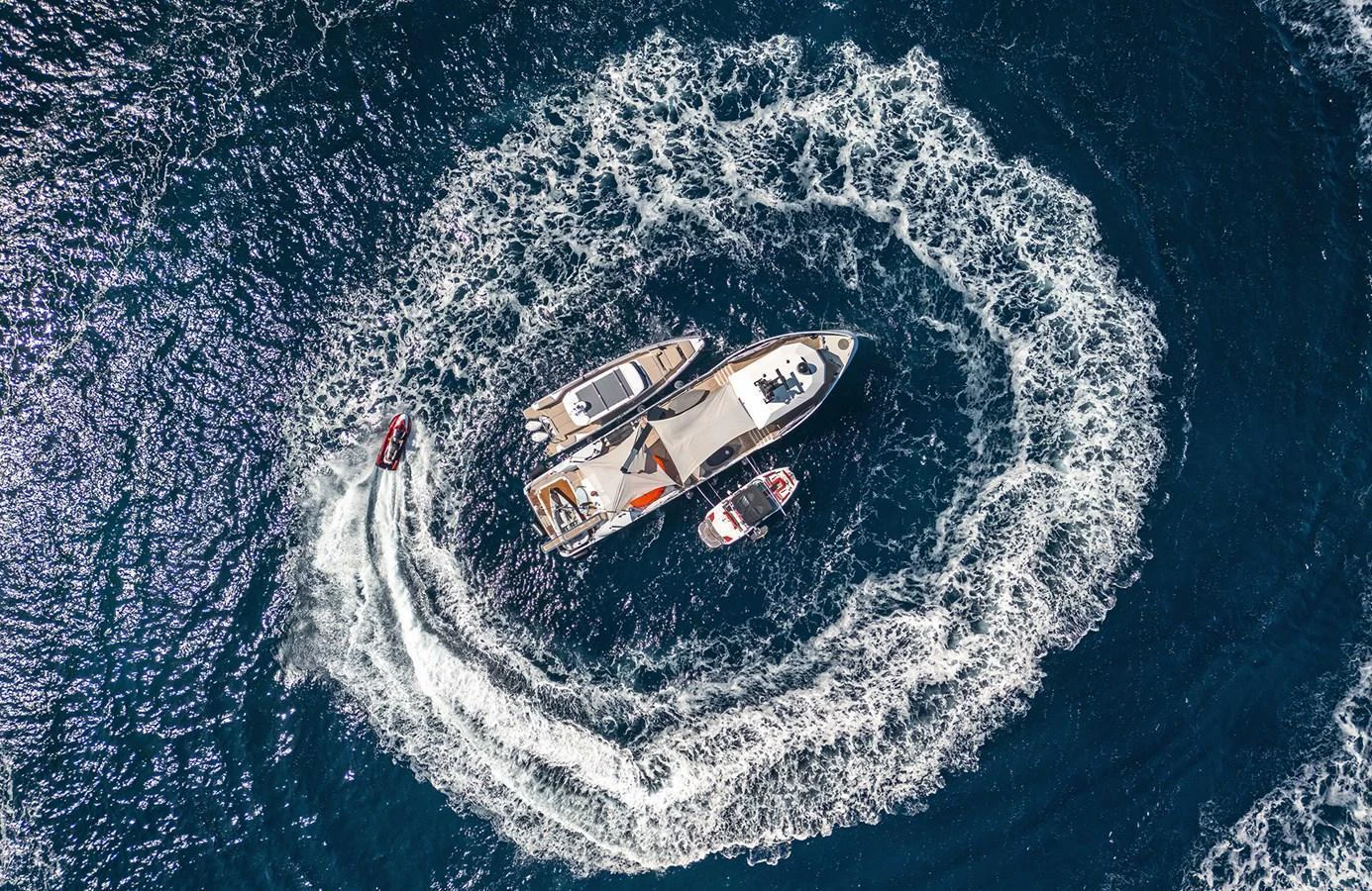Aerial view of a yacht surrounded by swirling water, accompanied by smaller boats. aboard 20 YXT Yacht for Sale