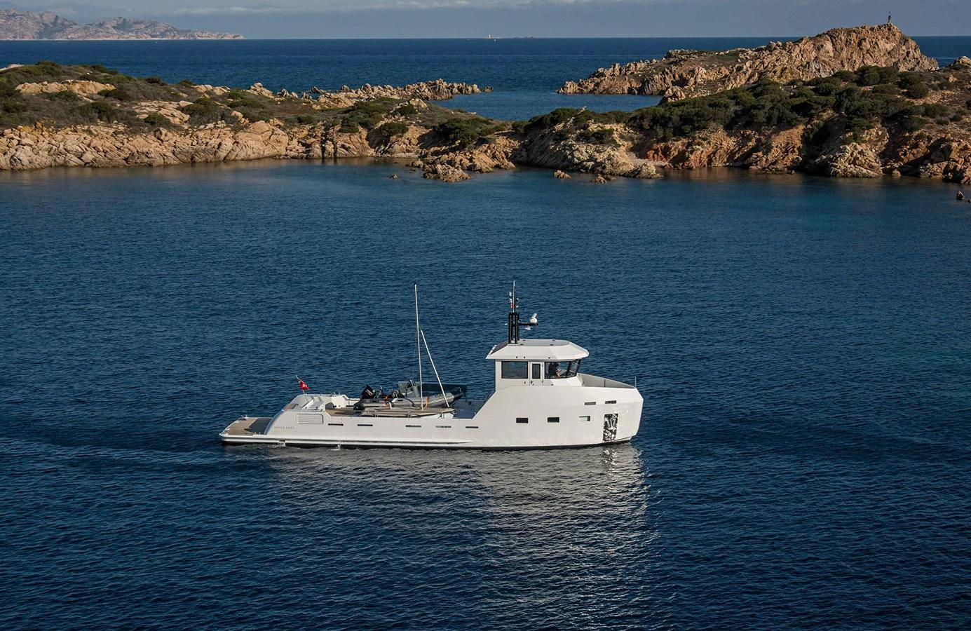 A sleek yacht cruises through calm blue waters near a rocky coastline. aboard 20 YXT Yacht for Sale