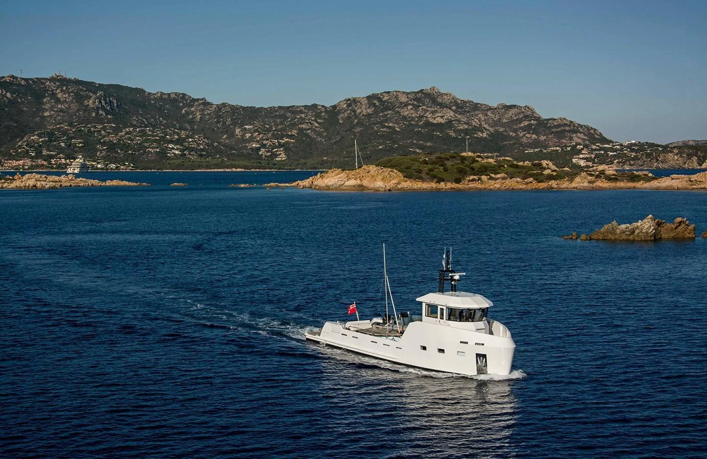 A sleek yacht cruises through calm blue waters with a scenic mountainous backdrop. aboard 20 YXT Yacht for Sale