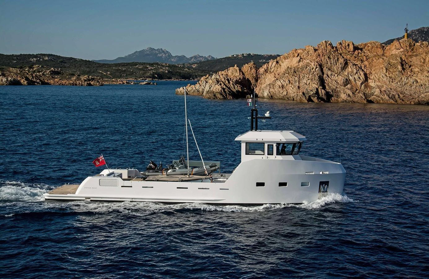 A sleek, modern yacht cruises along a rocky coastline under clear skies. aboard 20 YXT Yacht for Sale