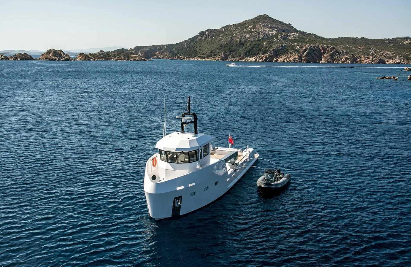 A sleek white yacht anchored in a serene bay with a tender alongside. aboard 20 YXT Yacht for Sale