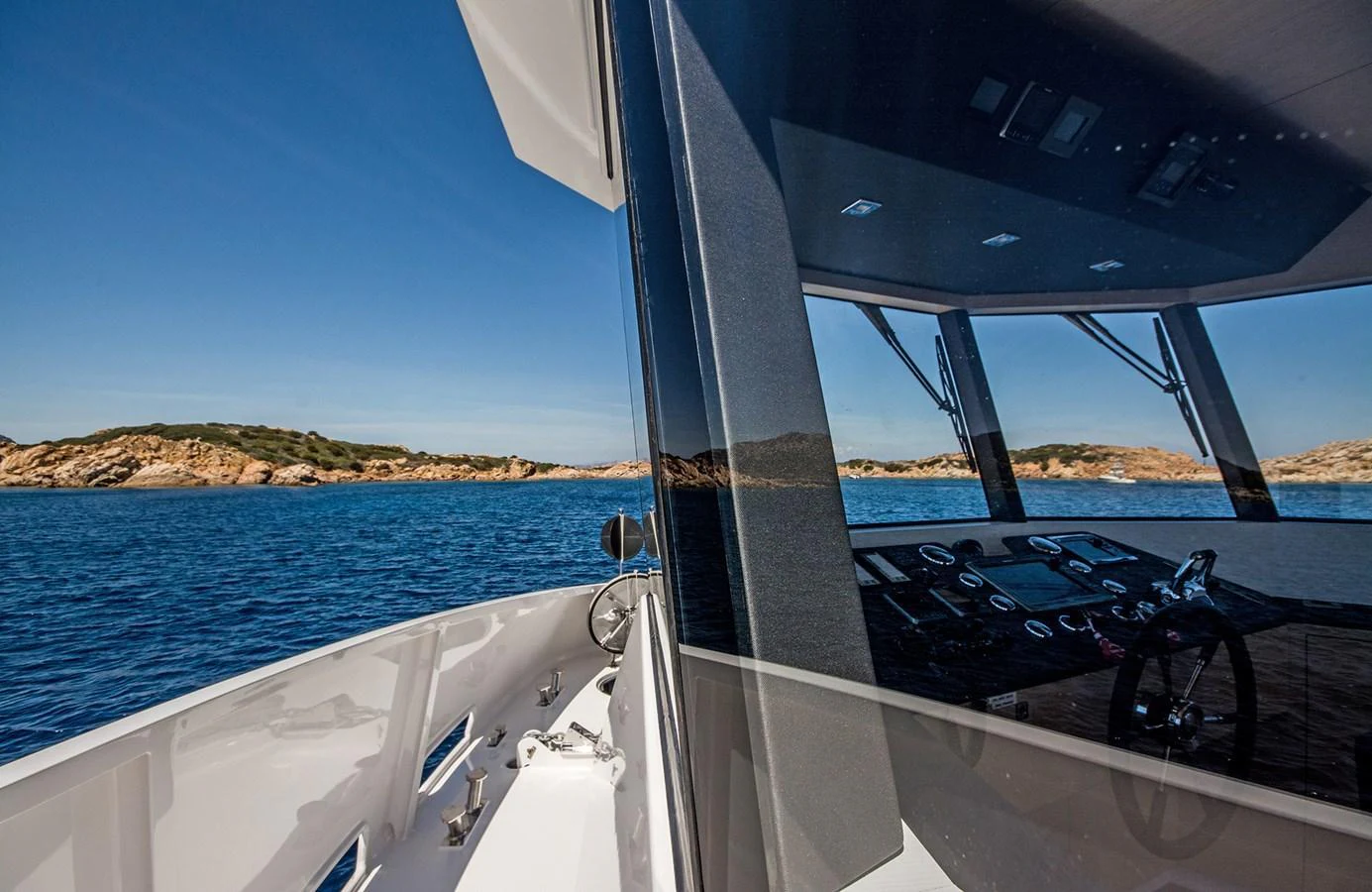 The yacht's sleek exterior is reflected in the glass, showcasing a beautiful coastal backdrop. aboard 20 YXT Yacht for Sale