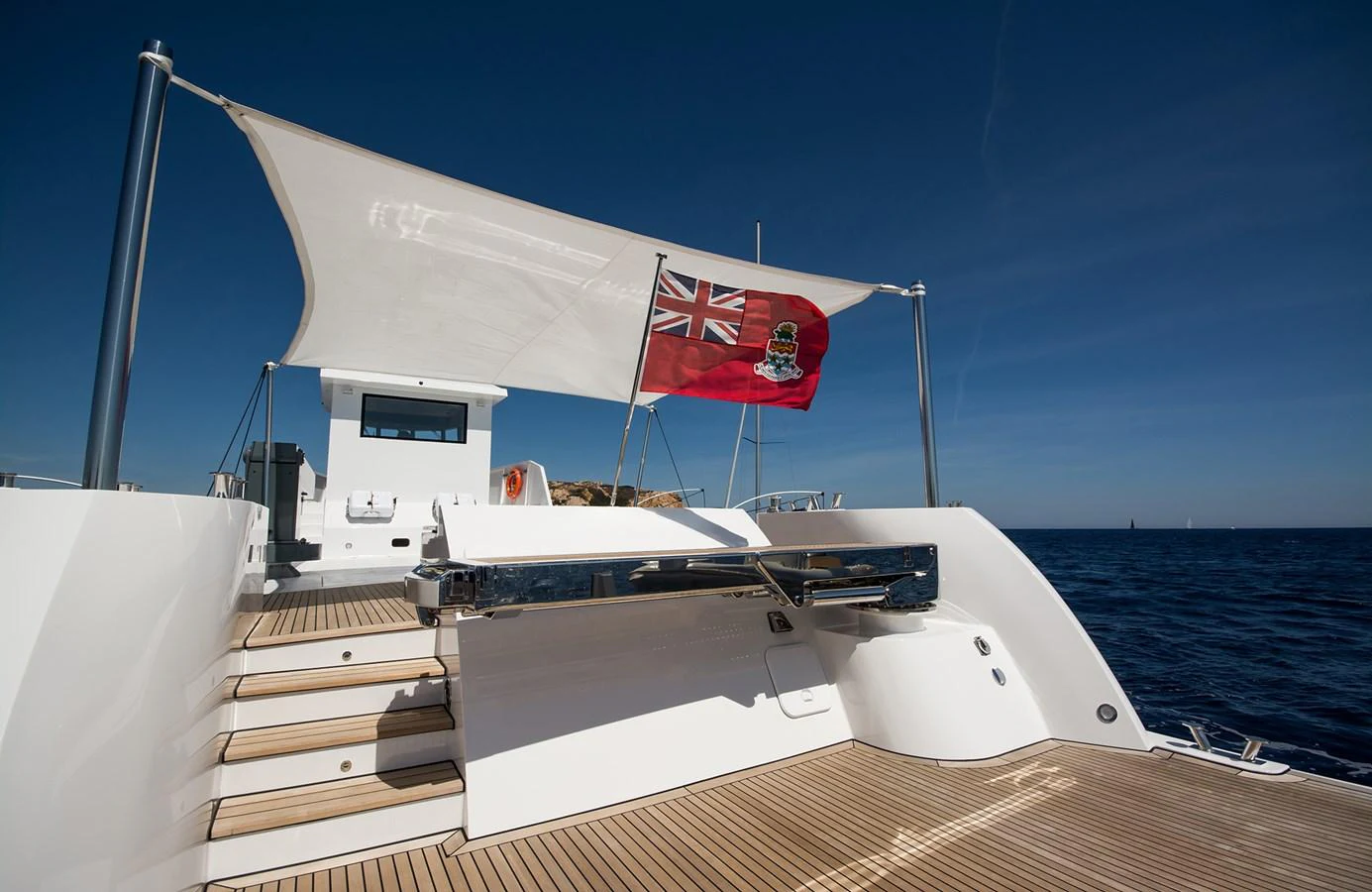 The yacht's aft deck features a sleek design with a flag flying under a clear blue sky. aboard 20 YXT Yacht for Sale