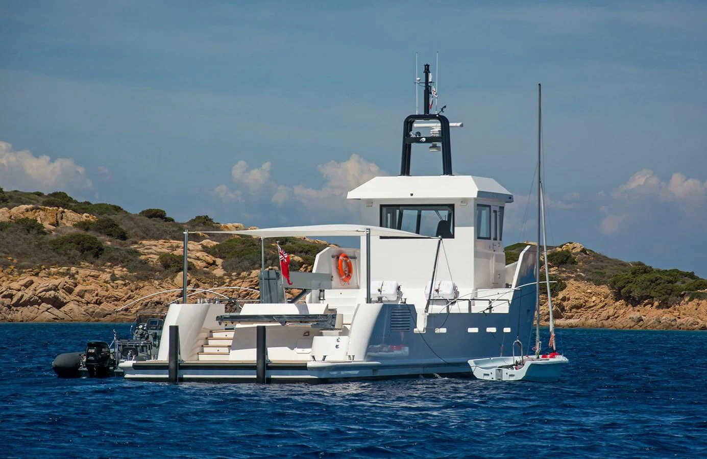 A sleek yacht anchored near a rocky shoreline under a clear sky. aboard 20 YXT Yacht for Sale