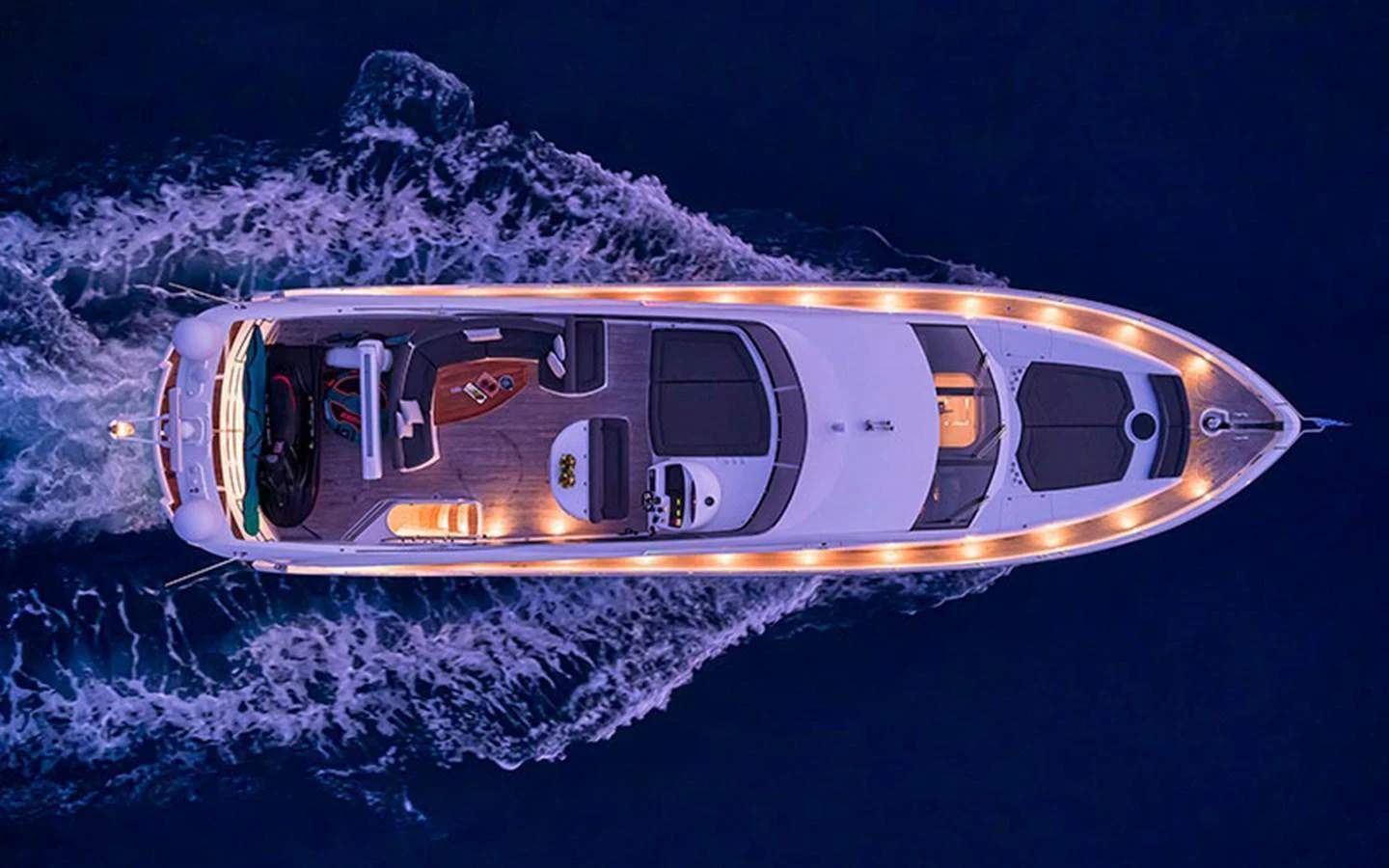 A stunning aerial view of a luxury yacht cruising through the water at night, illuminated by elegant lighting. aboard M FIVE Yacht for Sale