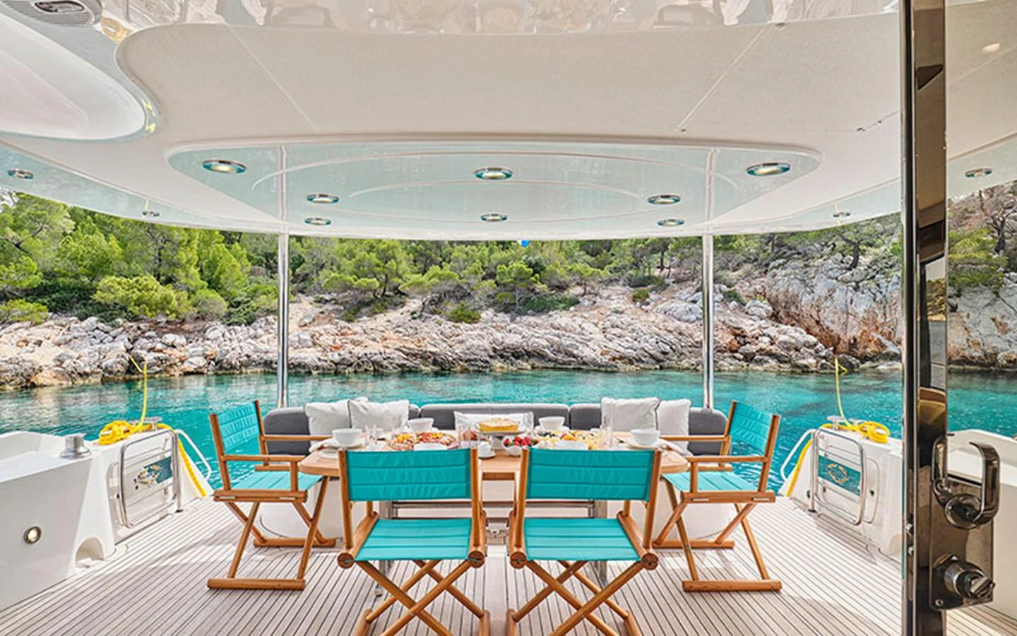 The aft deck features a spacious dining area with a stunning view of the surrounding waters and lush greenery. aboard M FIVE Yacht for Sale