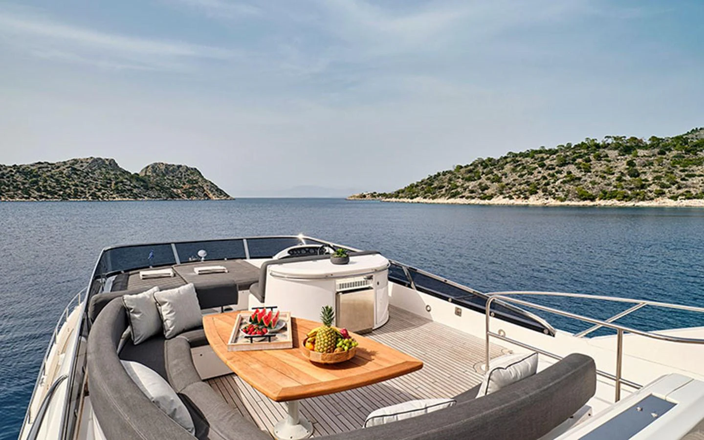 The yacht's foredeck features a luxurious seating area with a table set for relaxation and dining, surrounded by stunning sea views. aboard M FIVE Yacht for Sale