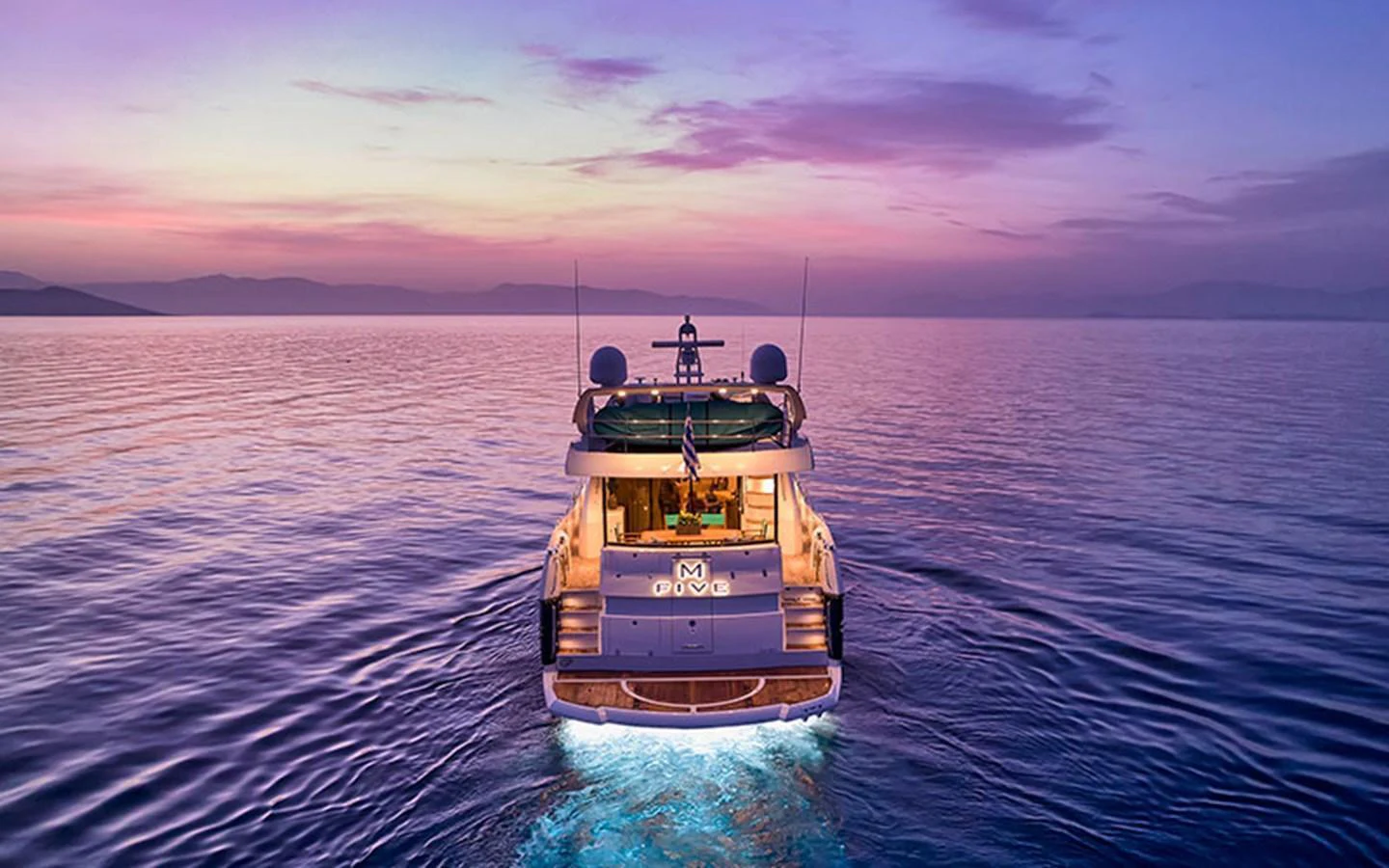 A luxurious yacht is seen cruising at sunset, creating a serene and picturesque scene on the water. aboard M FIVE Yacht for Sale