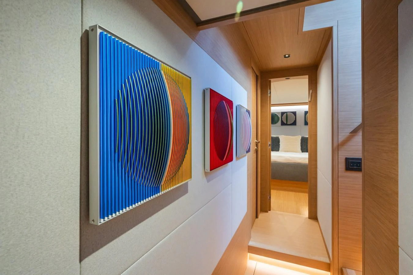 A stylish hallway adorned with modern art leads to a cozy stateroom. aboard SIMON Yacht for Sale