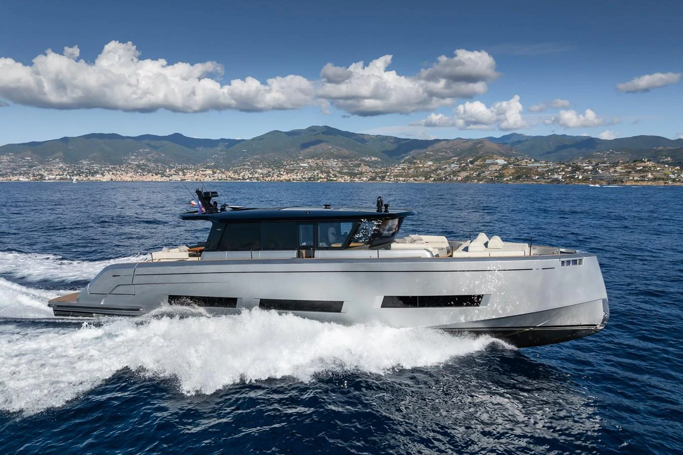 A sleek, modern yacht cruises through the water with a scenic coastline in the background. aboard SIMON Yacht for Sale