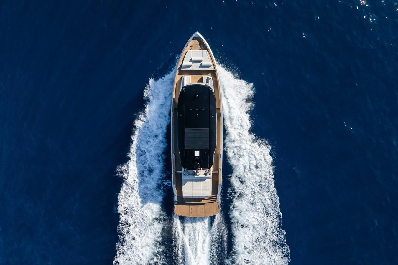 A sleek yacht cruises through deep blue waters, leaving a trail of white wake behind. aboard SIMON Yacht for Sale