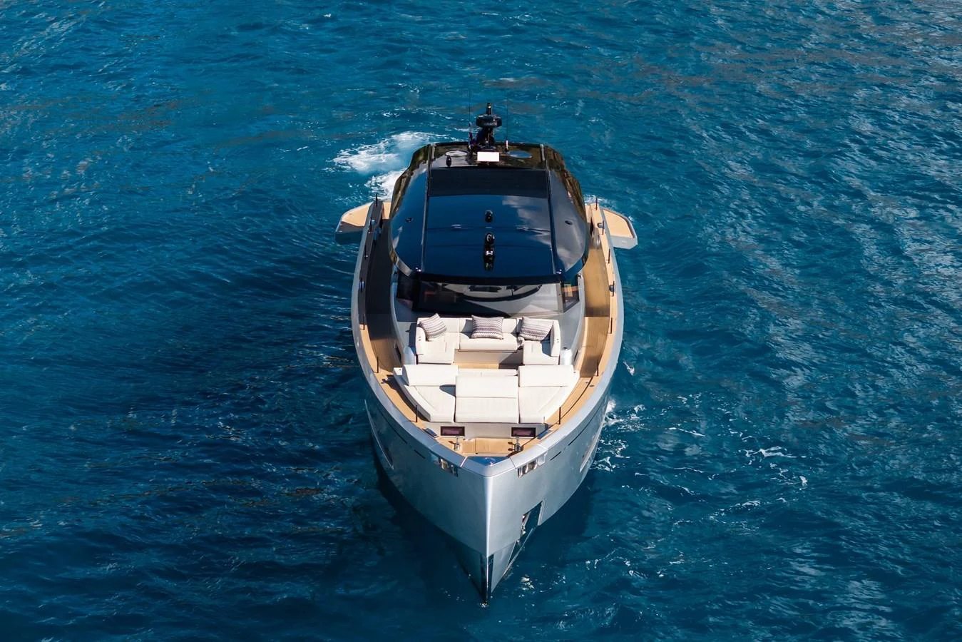 A sleek yacht glides through the vibrant blue waters, showcasing its modern design and spacious deck. aboard SIMON Yacht for Sale