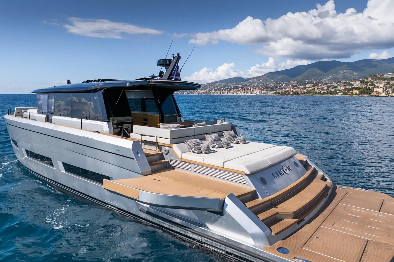 A sleek, modern yacht cruising on calm waters with a scenic coastal backdrop. aboard SIMON Yacht for Sale