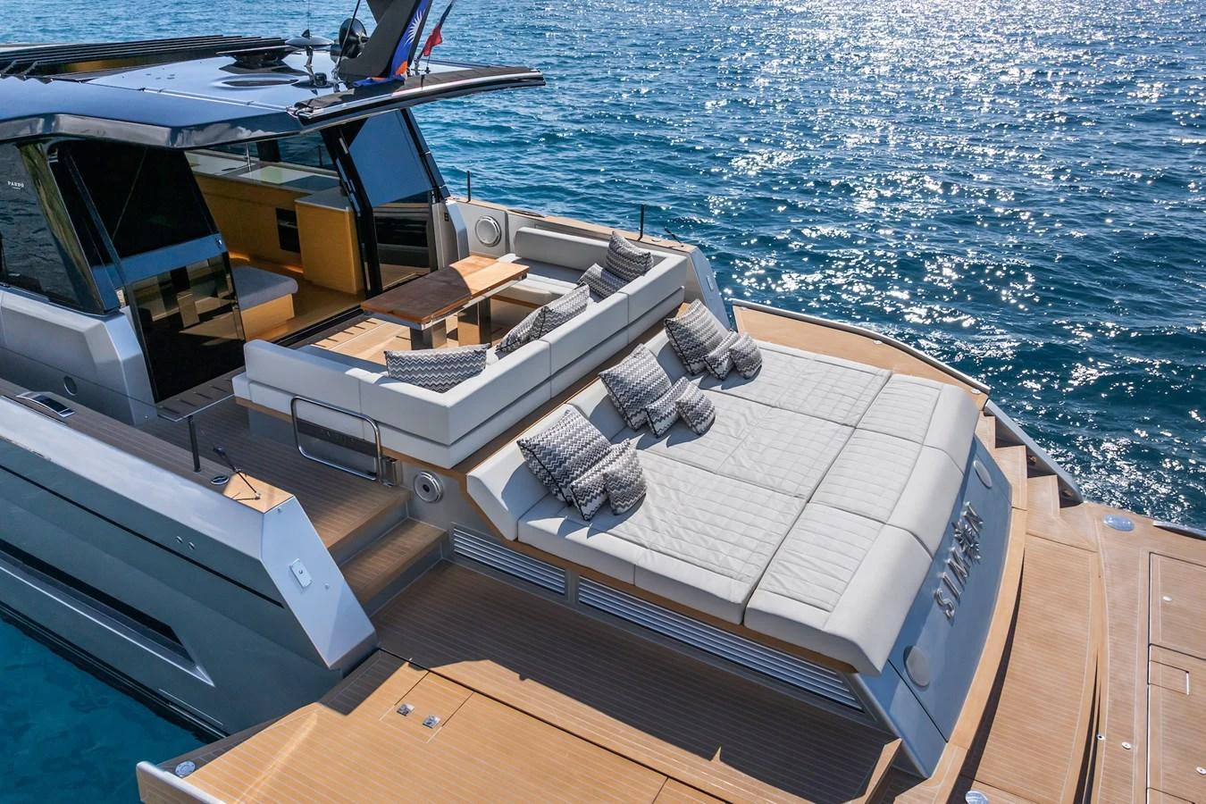 The yacht's aft deck features a luxurious sunbathing area with plush cushions and a dining space overlooking the serene water. aboard SIMON Yacht for Sale