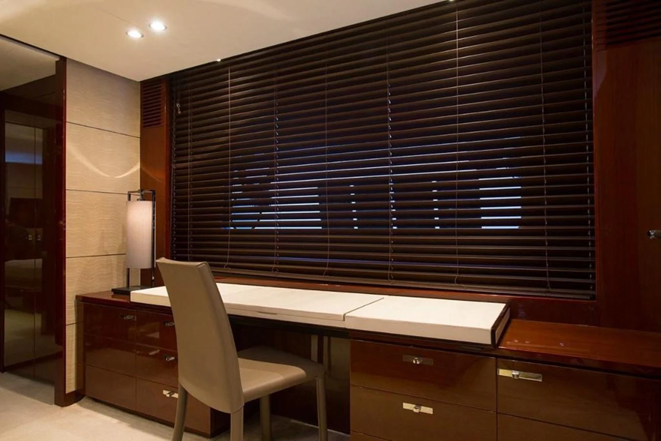 A sophisticated office space with a sleek desk and modern chair, complemented by dark blinds and warm lighting. aboard RAINBOW Yacht for Sale