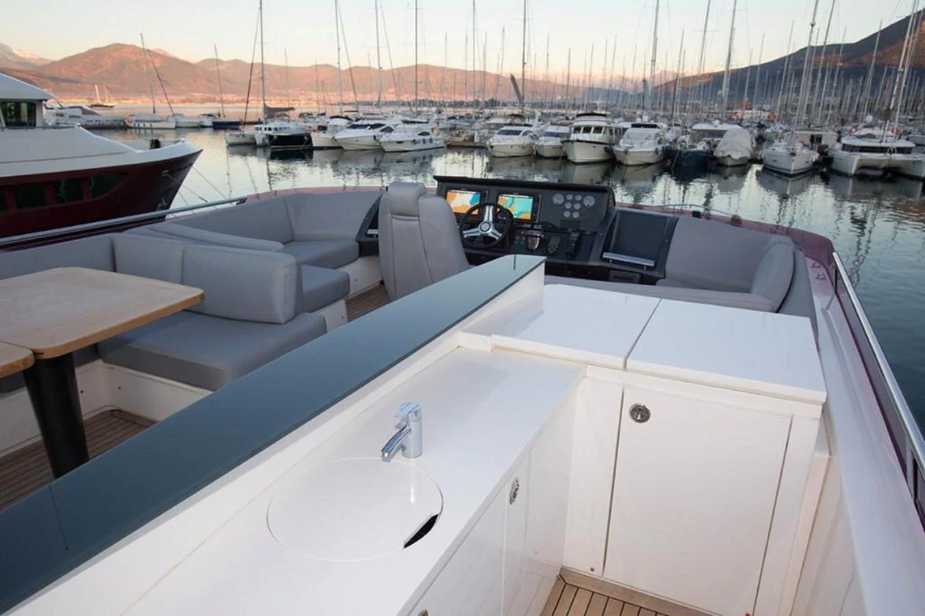 The flybridge offers a spacious seating area with a helm station and a small sink. aboard RAINBOW Yacht for Sale