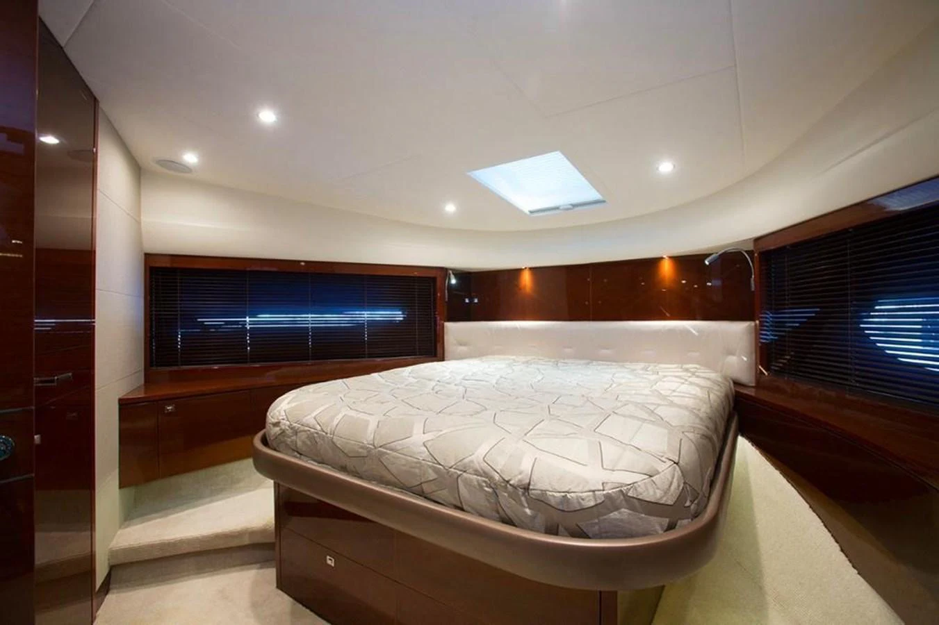The stateroom features a luxurious bed with elegant wood finishes and ample natural light. aboard RAINBOW Yacht for Sale