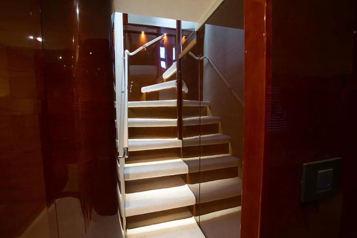 A luxurious staircase with polished wood paneling and soft lighting. aboard RAINBOW Yacht for Sale