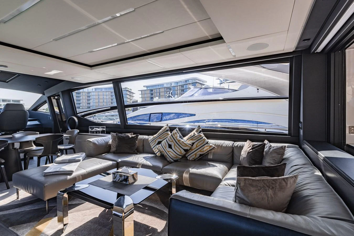 The salon features a spacious and modern seating area with large windows offering a view of the marina. aboard 2021 PERSHING 8X Yacht for Sale
