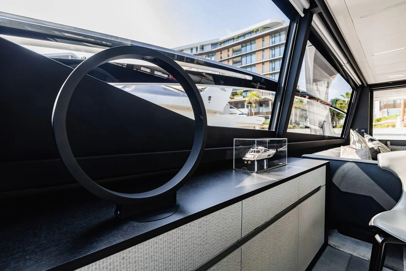 A modern yacht interior featuring a sleek design with a model yacht display and large windows offering a view of the marina. aboard 2021 PERSHING 8X Yacht for Sale