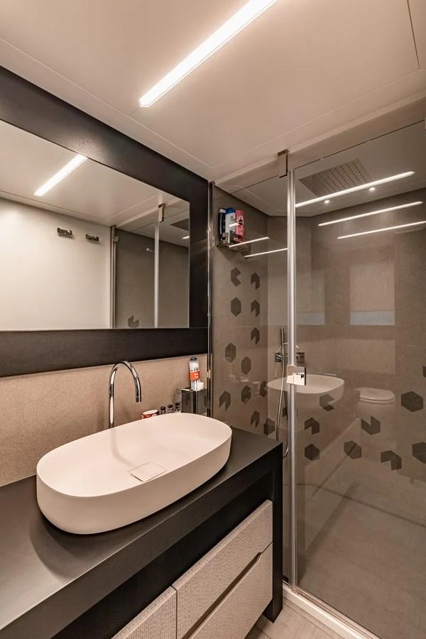 The yacht's bathroom features a modern design with a sleek sink and a glass-enclosed shower. aboard 2021 PERSHING 8X Yacht for Sale