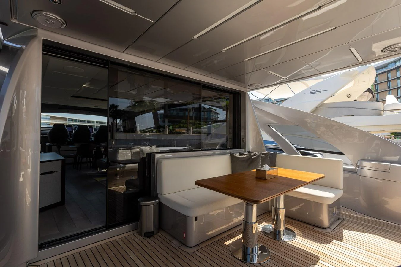 The aft deck features a stylish dining area with a wooden table and comfortable seating, perfect for alfresco meals. aboard 2021 PERSHING 8X Yacht for Sale