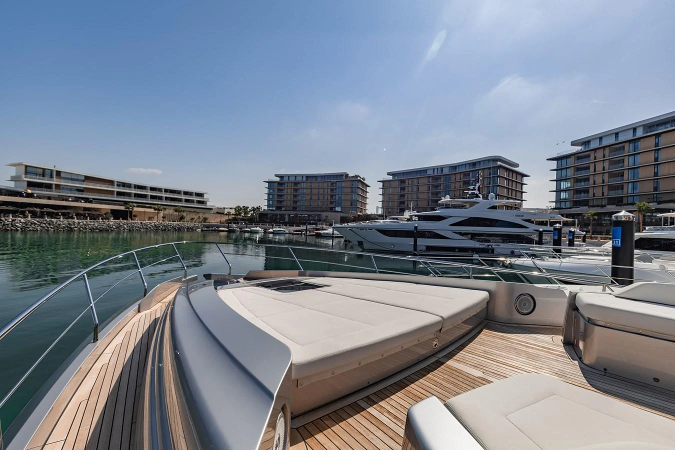 The foredeck of the yacht offers spacious sun pads with a scenic marina backdrop. aboard 2021 PERSHING 8X Yacht for Sale